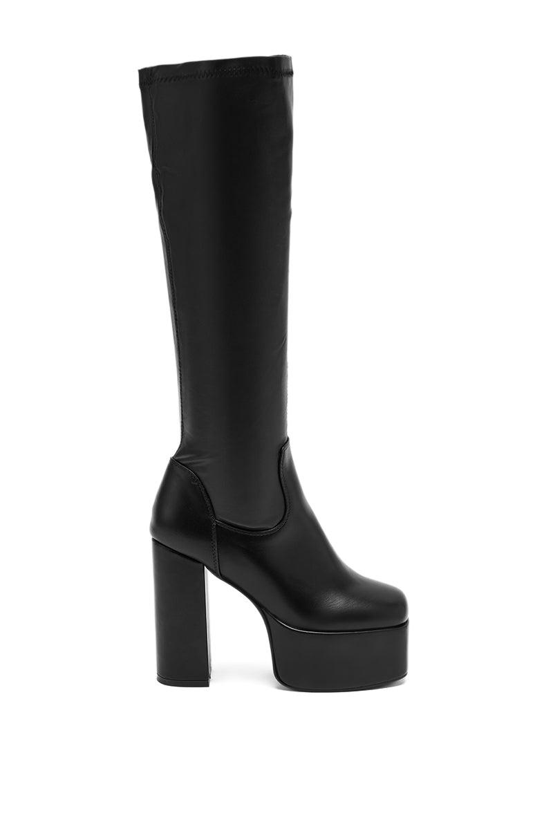 The AZALEA WANG BOMBON BLACK STRETCH PU CHUNKY BOOT is a black knee-high boot with a chunky platform heel, round toe, and smooth faux leather finish, shown in side profile on a white background. 2