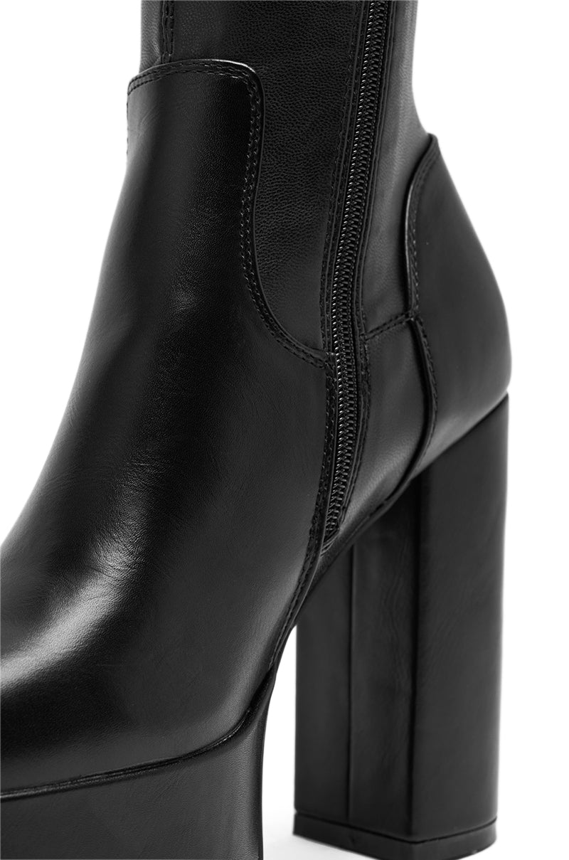 Close-up of the AZALEA WANG BOMBON Black Stretch PU Chunky Boot, featuring a knee-high design, high chunky heel, and visible side zipper, shown against a white background. 5