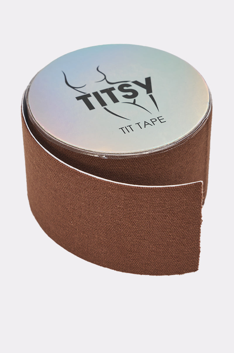 A roll of TITSY ULTRA LIFT BOOB TAPE IN DARK with a silver lid and stylized breast outline, partially unrolled on a light background. This discreet tape provides lift, ideal for backless outfits. 0