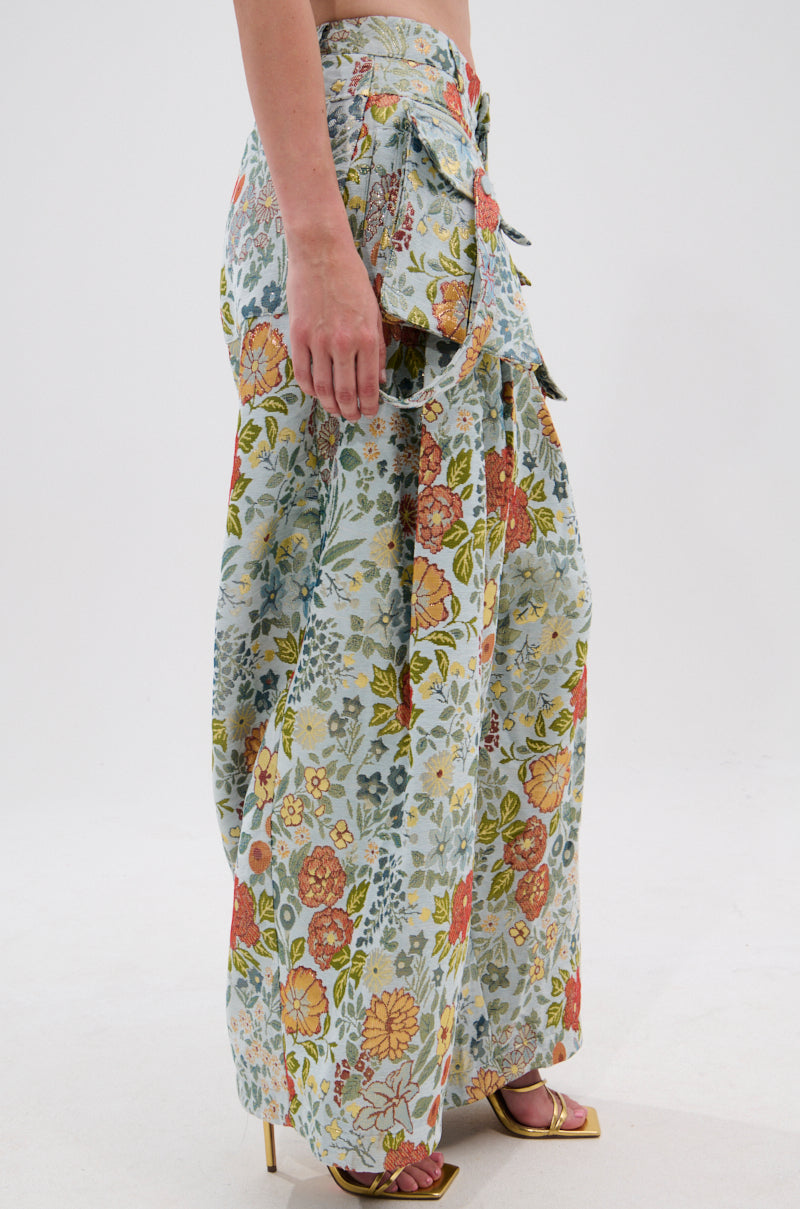 A person models the MARTHA FLORAL CARGO PANTS—wide-leg, high-waisted with large side pockets—paired with gold open-toe heels, standing against a plain white background. 2