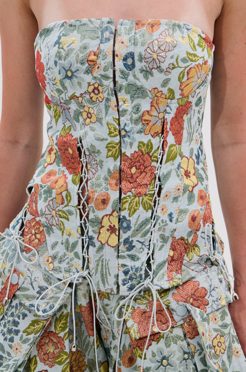A close-up of the MARTHA FLORAL CORSET, a strapless, fitted dress with a multicolor floral tapestry pattern, featuring decorative white laces and front buttons.