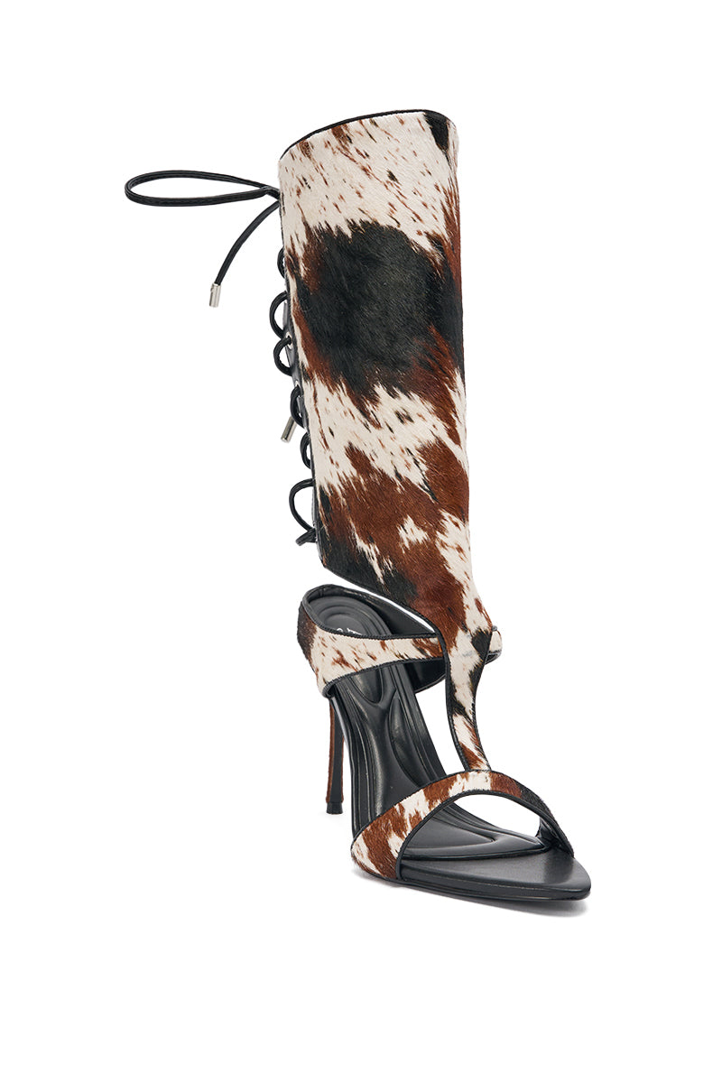 The AKIRA GOLD CALF HAIR LACE UP GLADIATOR STILETTO SANDAL showcases a knee-high cow print design with a stiletto heel, open toe, black sole, lace-up front, and stylish back-tie closure. 4