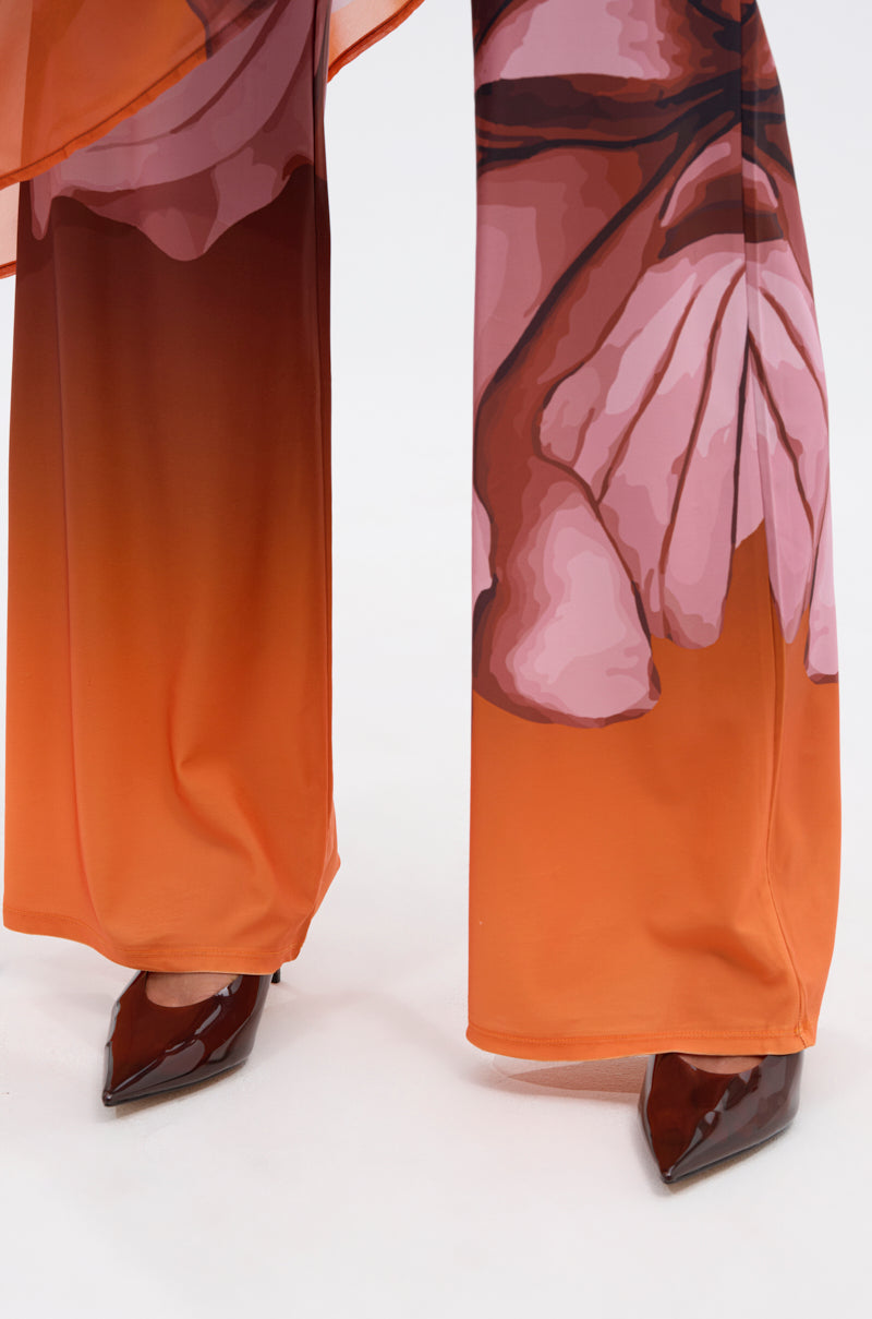 The ON A BEACH SOMEWHERE PRINTED JUMPSUIT IN ORANGE features wide, flowing legs and a tropical floral print—paired with brown patent leather heels, it’s perfect for summer parties or beach getaways. 6