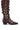 Side view of the AZALEA WANG BRAULIA BROWN CROC WESTERN BOOT, showcasing a knee-high design with crocodile-textured brown leather. The boot is adorned with multiple gold buckles running vertically along its length and across the ankle, featuring a pointed toe and a short, chunky black heel.