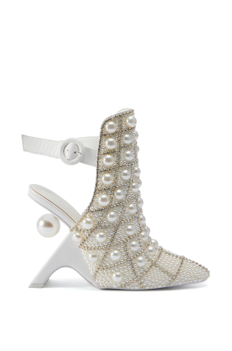 The AZALEA WANG BREAN EMBELLISHED PUMP is a white high-heeled shoe adorned with pearl beads and rhinestone embellishments, featuring a unique sculpted heel that incorporates a large pearl. The faux leather upper has a slingback strap with a circular buckle and a pointed toe design, exuding luxurious and intricate detailing that suggests high fashion.