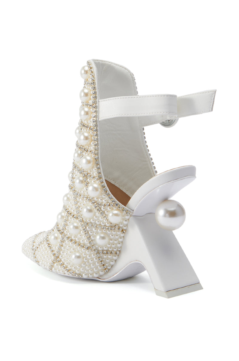 The AZALEA WANG BREAN EMBELLISHED PUMP is a white high-heeled shoe adorned with pearls, featuring a back strap and a distinctive bulbous pearl at the base of the heel for added decorative flair. Its faux leather upper exudes a luxurious and elegant aesthetic.
