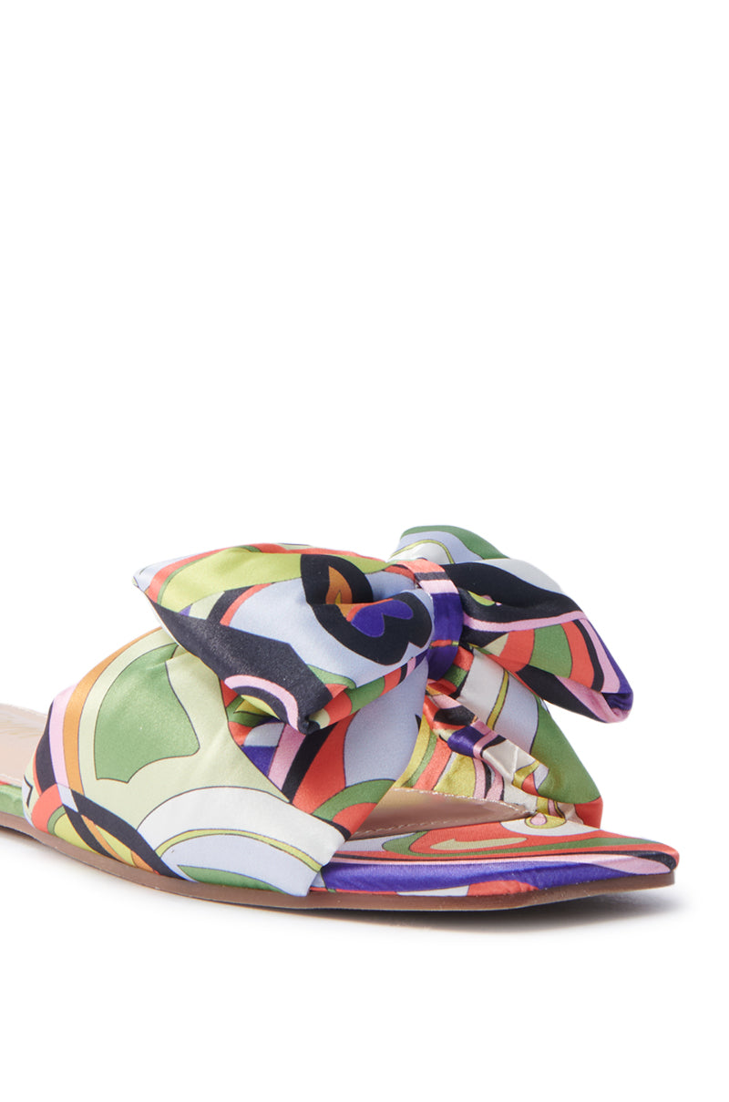 Introducing the Breezy Scarf Flat Sandal in Chartreuse: a vibrant sandal with a colorful abstract pattern and large bow. It features shades of green, orange, purple, and blue on a satin open square-toe design, offering comfort with its flat sole and elegant open toe.