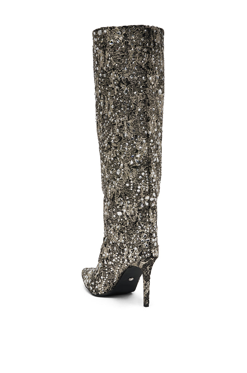 The AZALEA WANG BRIELEY GOLD AND BLACK FLORAL BROCADE KNEE HIGH BOOT features a pointed toe and stiletto heel, with a textured gold and black floral brocade pattern that stands out against a plain white background. 5