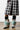 Sporting a chic look, the ensemble features legs clad in a black and white plaid skirt boasting a high slit, complemented by the AZALEA WANG BRIENNE MULTI BOOTIE. The outfit is enhanced with zebra print and pastel teal faux fur leg warmers layered over stylish black leggings.