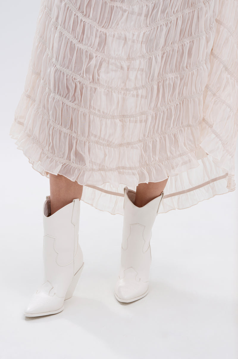 A person in a light, ruffled, knee-length skirt and AZALEA WANG BRIGGITTA WHITE WESTERN COWBOY BOOTIE stands on a white background for a Cowgirl Chic look.