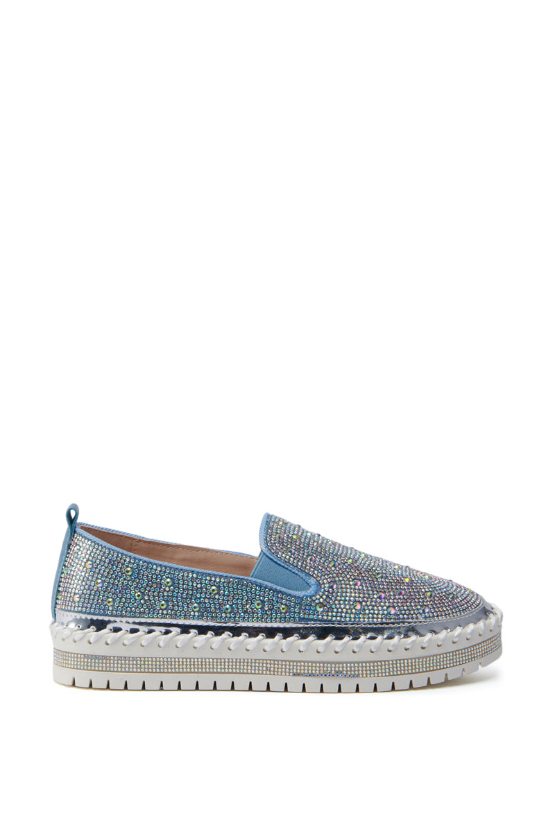 Side view of the AZALEA WANG BRITTANY DENIM RHINESTONE SNEAKER, showcasing its blue denim material adorned with multicolored rhinestones and a woven, espadrille-style flatform sole. The rubber outsole has a tread pattern for grip, and a small pull tab on the heel allows for easy wear.