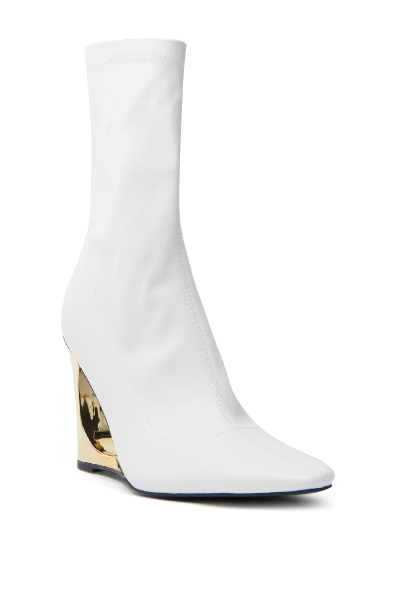 The AZALEA WANG BRIXHAM WHITE BOOTIE is a vegan leather sock boot featuring a pointed toe and high wedge heel. Its sleek white material is stylishly contrasted by a reflective gold novelty heel.