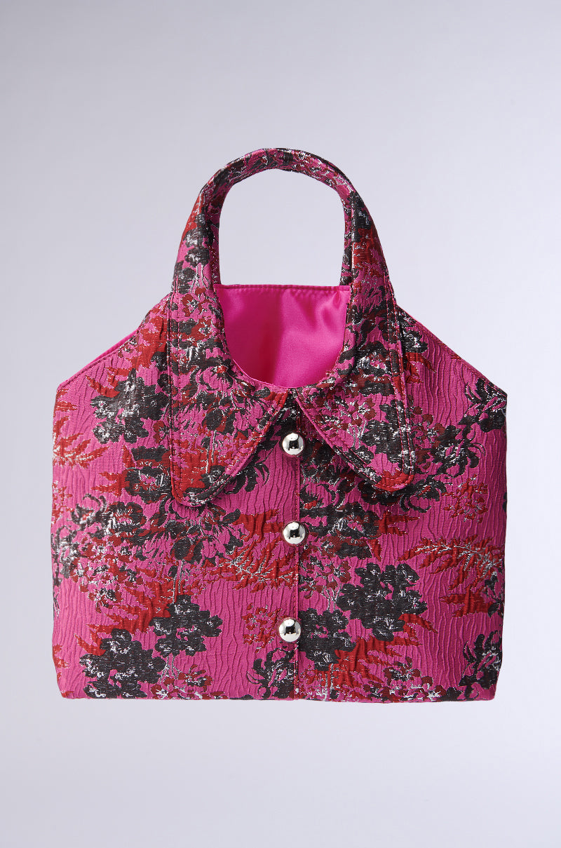 The DONT BE JEALOUS JACKET BAG is a pink brocade floral handbag with textured fabric, a shirt collar design, silver buttons, metallic accents, two short handles, and a bright pink satin lining.