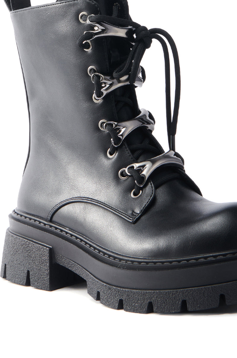 Close-up of the AZALEA WANG BROOKS BLACK COMBAT BOOTIE, featuring a rugged faux leather design with shiny metal eyelets, a thick treaded sole, partially tied laces, and a sleek chunky heel.