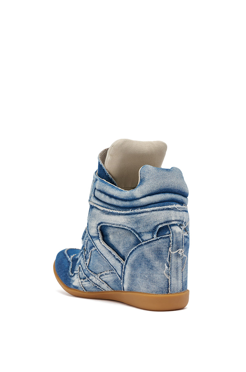 The AZALEA WANG BRYANT DENIM WEDGE SNEAKER is a high-top denim streetwear shoe with visible seams, a tan rubber sole, and is shown from the back/side. It features a padded collar and tongue for added comfort and style. 5