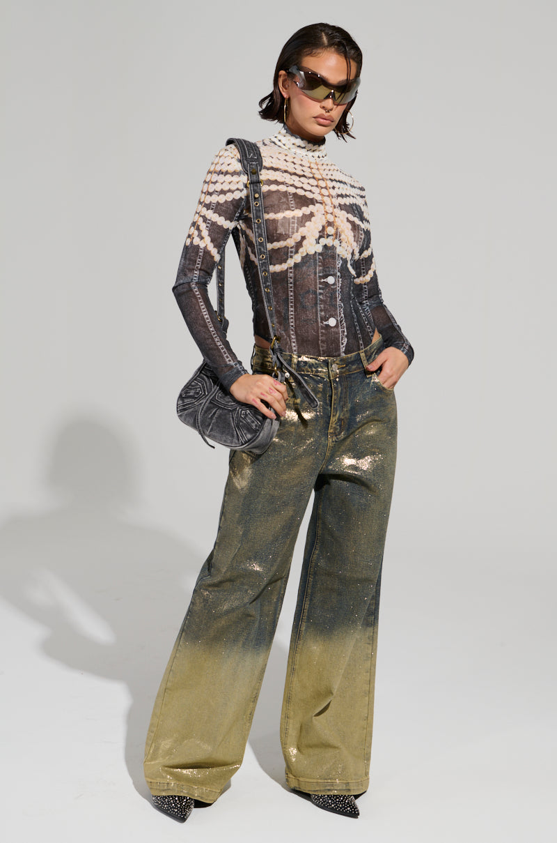 A person wearing shiny high-waisted wide-leg pants and the LOCKED IN BODYSUIT, accessorized with sunglasses and a black bag. The outfit is stylish and modern against a neutral background.