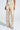 A person stands against a plain background wearing the LOTS OF LOVE SATIN PALAZZO PANT, featuring a high-waisted, wide-legged silhouette with beige and white abstract color blocking. They pair the stylish ensemble effortlessly with chic platform sandals.