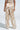 A person stands with their back to the camera, showcasing the LOTS OF LOVE SATIN PALAZZO PANT. These wide-legged pants feature a high-rise fit and an eye-catching color block abstract print in beige and white against a plain, light-colored backdrop.