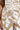 Close-up of someone in LOTS OF LOVE SATIN PALAZZO PANT, featuring a high-rise fit with a beige and white color block abstract print and drawstring. The person's hand partially appears on the left.