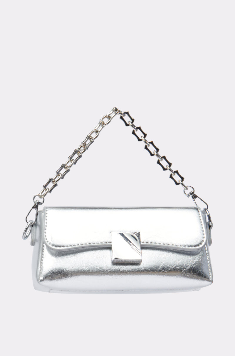 The ONLY THE BEST PURSE is a small metallic silver bag with a rectangular flap, geometric clasp, and a structured shape. It features a short chain-link handle for a chic finishing touch.