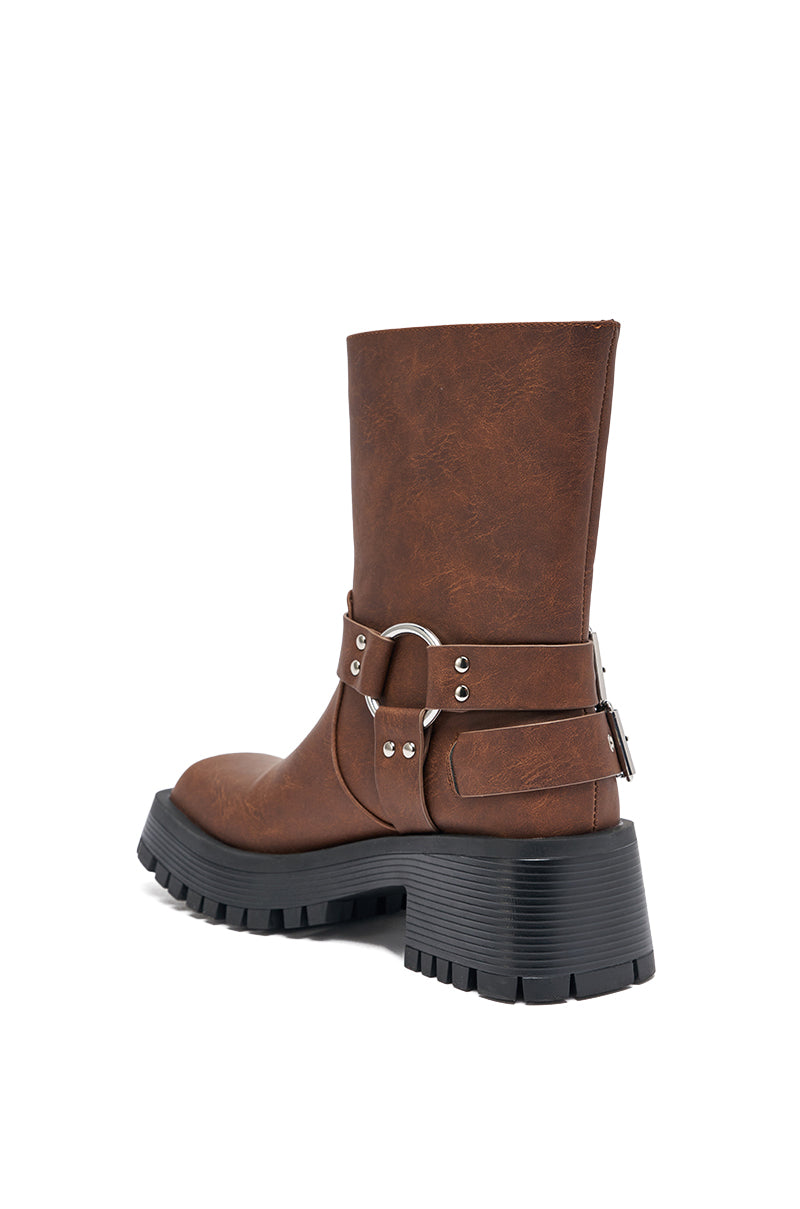 The AZALEA WANG BUCKED Brown Chunky Heel Combat Bootie features a brown faux leather upper, chunky black lug sole, ankle strap with silver hardware, and is shown mid-calf on a white background angled to highlight the side and back. 7