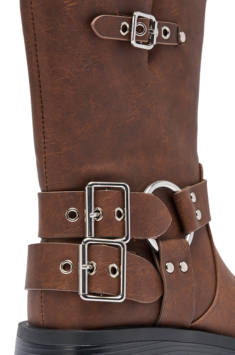 Close-up of the AZALEA WANG BUCKED BROWN CHUNKY HEEL COMBAT BOOTIE, a brown faux leather mid-calf boot with three silver buckles, decorative straps, ring detail, chunky heel, black sole, and visible stitching showcasing textured leather. 8
