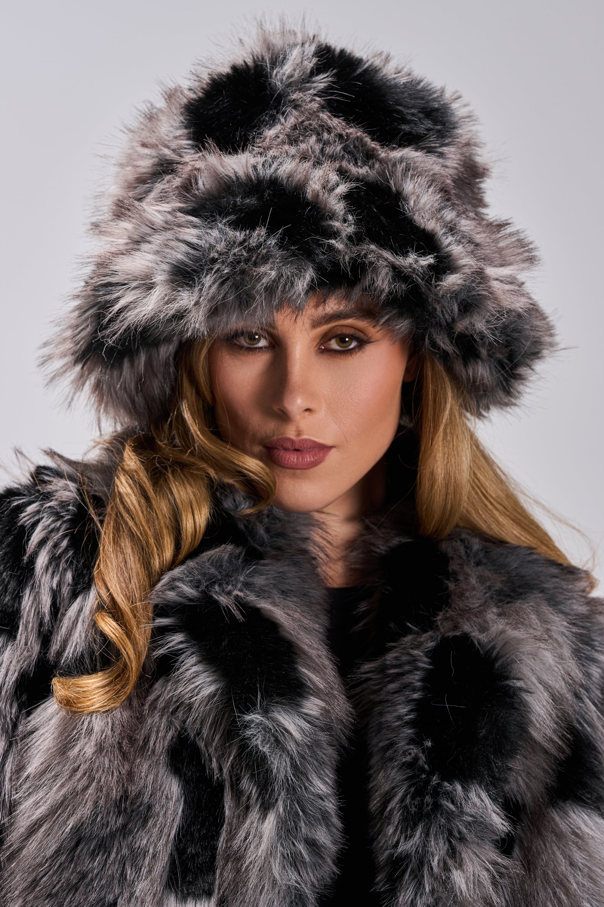 A woman with long blonde hair models the ARLO FAUX FUR BUCKET HAT and a matching faux fur coat, gazing neutrally at the camera against a plain background—a chic winter accessory ensemble.