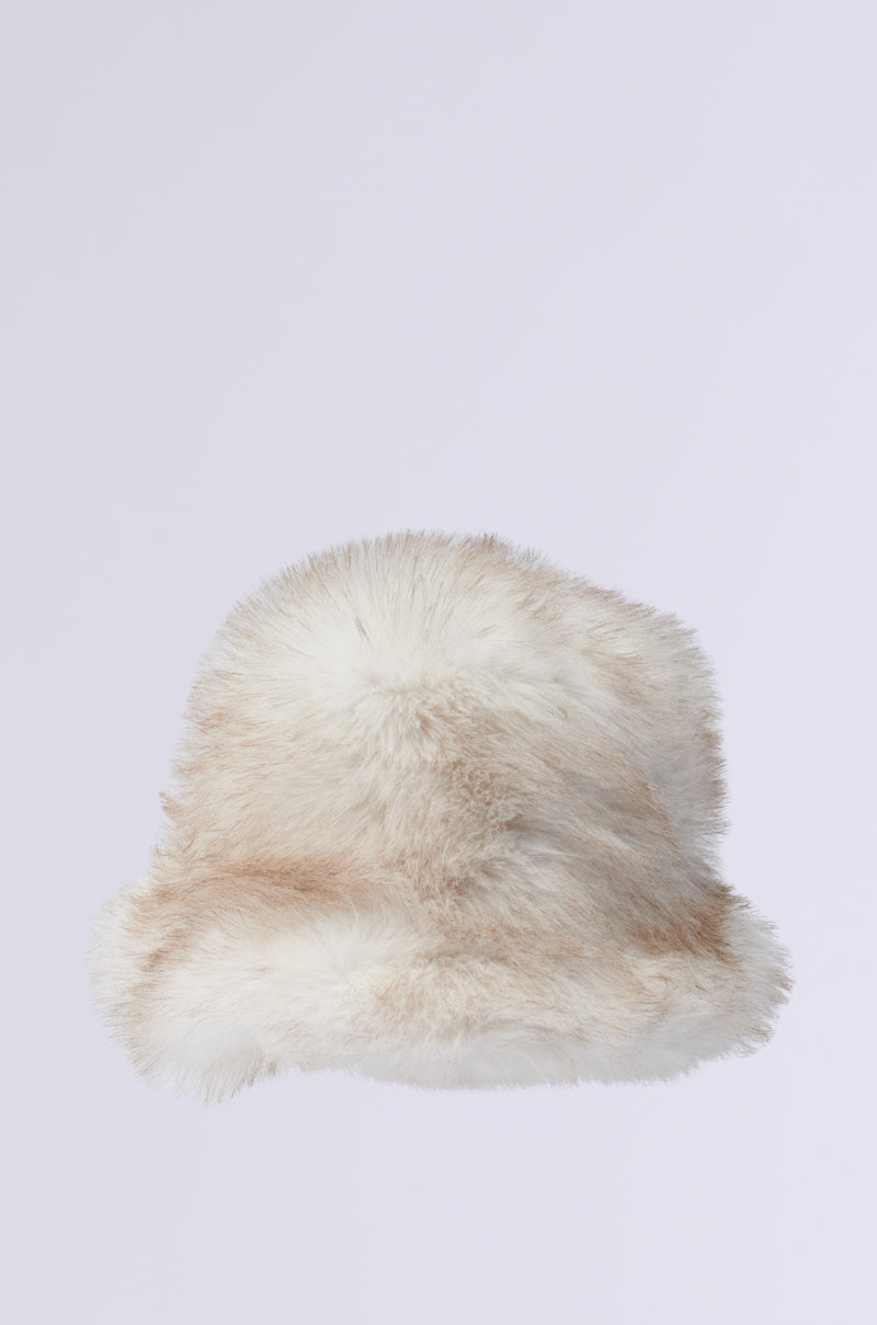 The TOASTIE FAUX FUR BUCKET HAT is a stylish accessory featuring a fluffy, soft texture in white and light brown against a simple gray backdrop. This cozy hat exudes warmth, making it perfect for chilly weather.