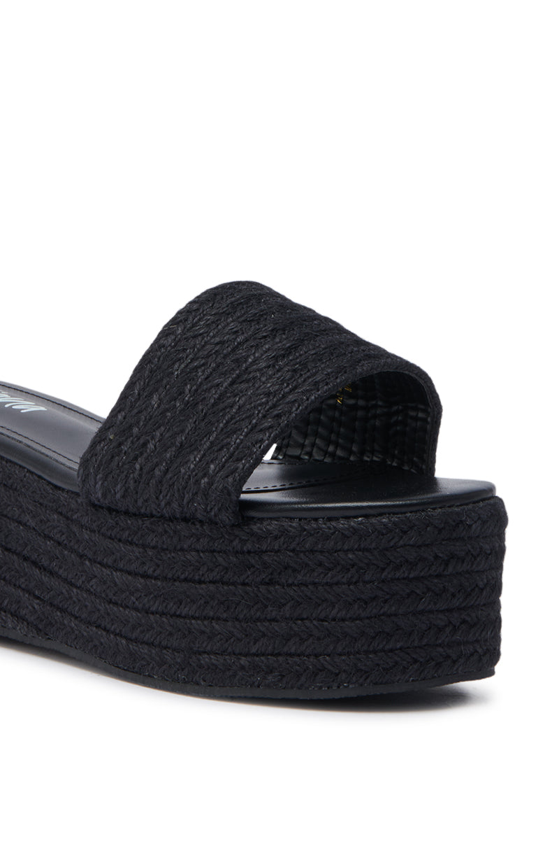 Close-up of the BUDZA BLACK FLATFORM SANDAL, showcasing its black rattan finish, woven strap texture, flatform sole, and open almond toe design.