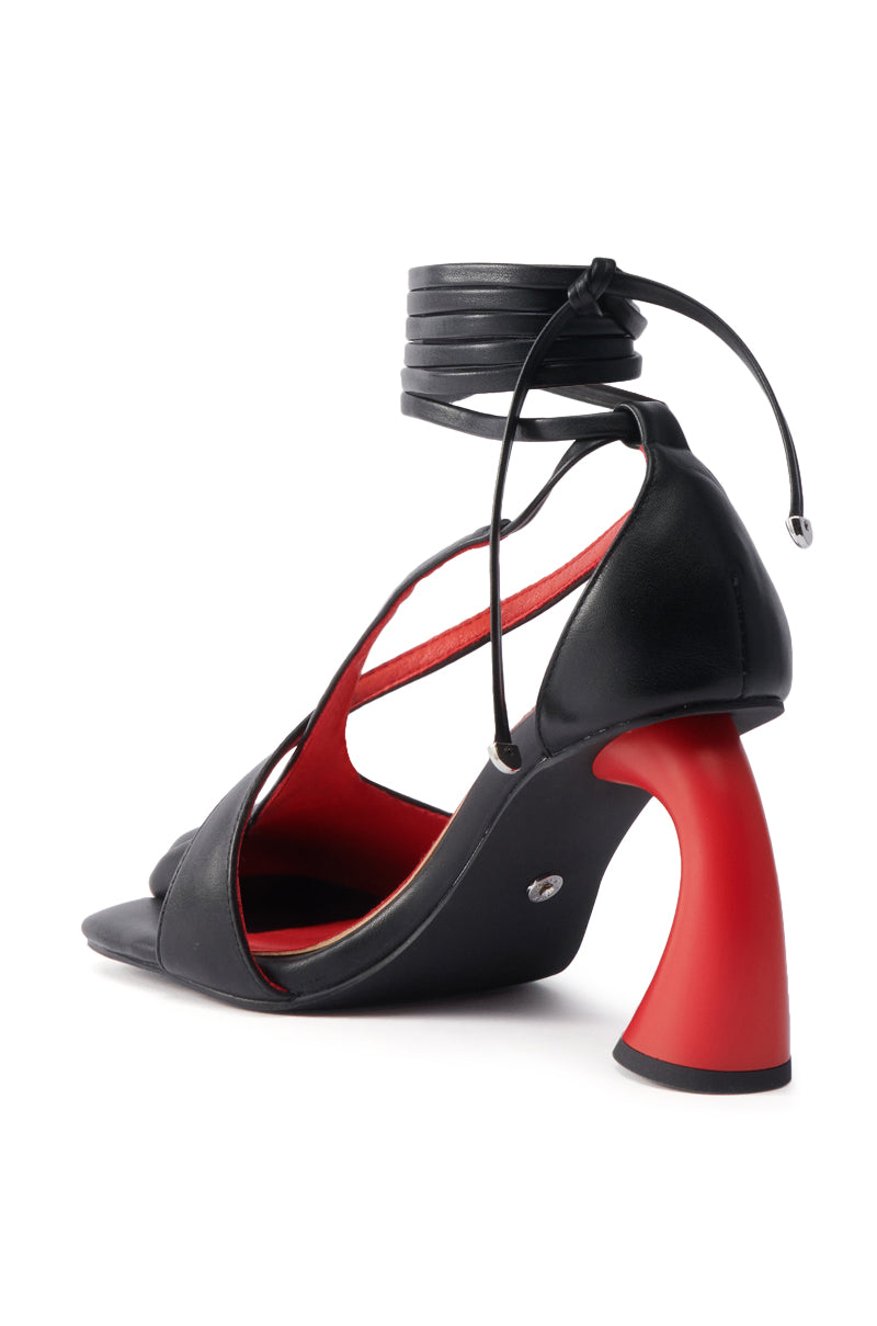 The AZALEA WANG BUIKY BLACK AND RED PUMP features a bold chunky sculptural red heel, black faux leather wrap-around ankle straps, and a striking red interior lining for a stylish standout look.
