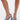 A close-up of a person wearing the AZALEA WANG BUIKY DENIM PUMP, featuring criss-cross self-tie denim straps around the ankles and curved blue chunky sculpted heels, set against a clean white background.