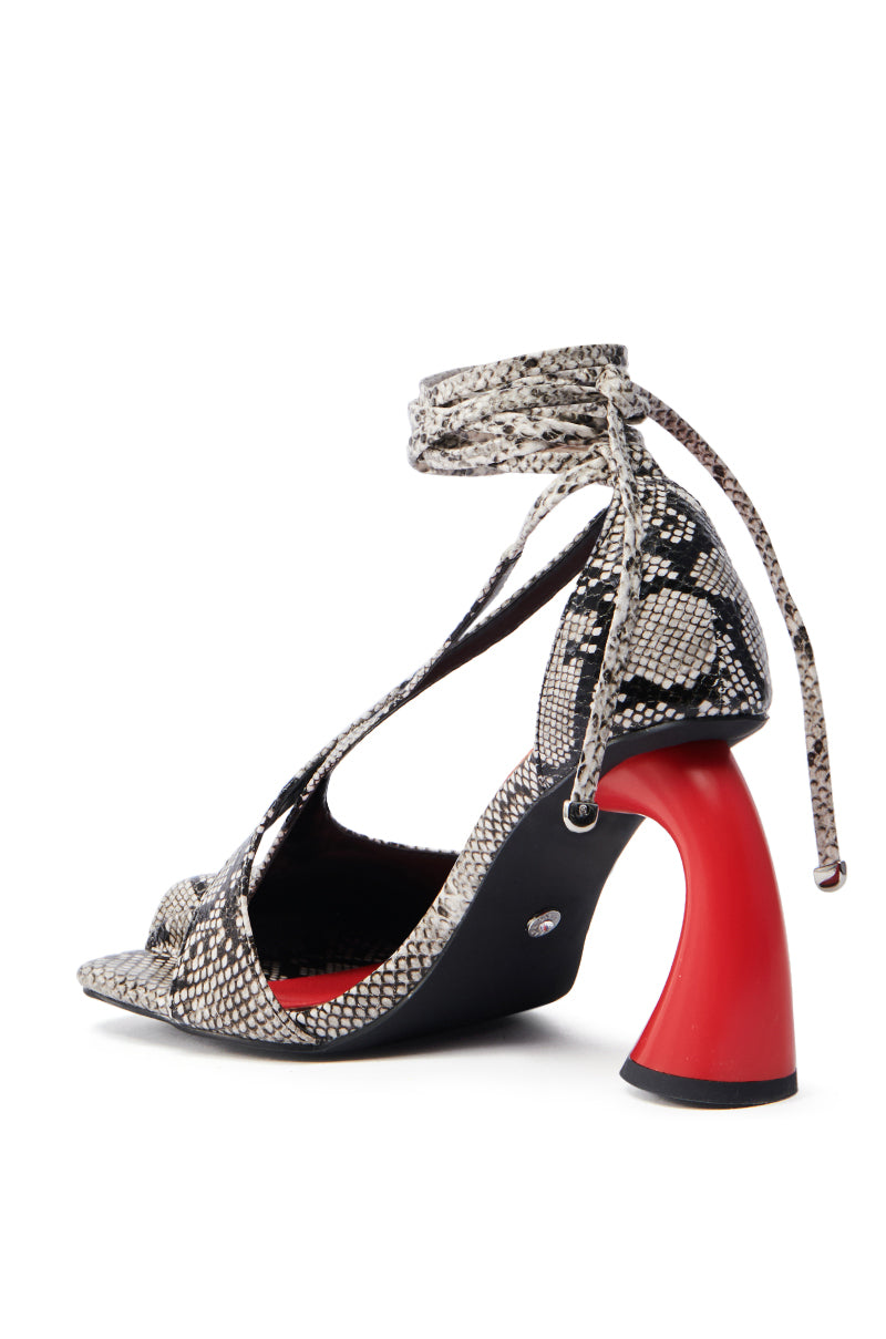 The AZALEA WANG BUIKY SNAKE CONTRAST CURVED HEEL OPEN TOE PUMP features a faux snakeskin pattern, criss-crossing straps, wraparound ankle laces, and a unique red curved heel. Its red interior adds bold contrast to this chic design.