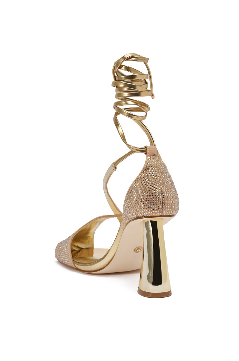 The AZALEA WANG BUILANY GOLD RHINESTONE CHUNKY PUMP features a sparkling rhinestone upper, open toe, metallic block heel, and ankle wrap with strappy lace-up coiled straps for a bold, glamorous look.