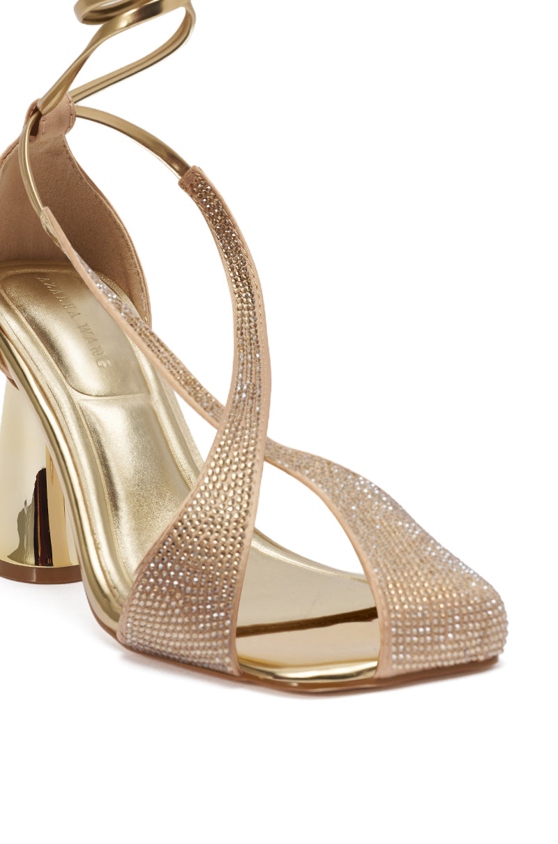 The AZALEA WANG BUILANY GOLD RHINESTONE CHUNKY PUMP is a metallic gold, open-toe sandal with crisscross rhinestone straps, an ankle wrap strap, and a chic block heel—perfect for adding elegance to any occasion.