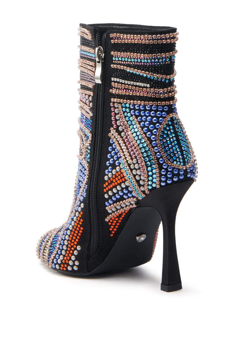 The AZALEA WANG BYRE bootie is an open-toe, high-heeled ankle boot adorned with colorful rhinestones in geometric patterns. It features a side zipper and slender black stiletto heel, embellished with blue, orange, and white beads for an eye-catching finish.
