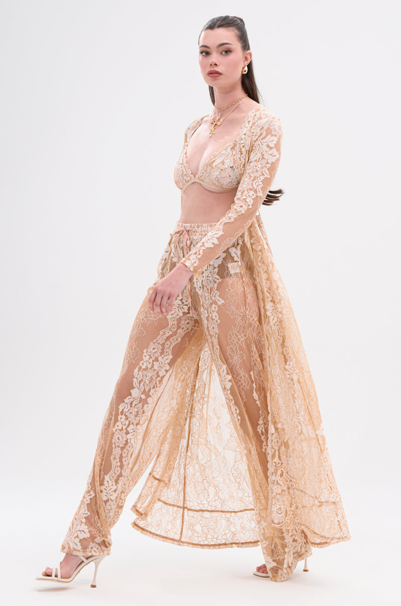 A woman models the RESORT VIBES WIDE LEG PALAZZO PANT with a matching light beige sheer lace robe and bralette, accessorized with high-heeled sandals and gold jewelry, her hair pulled back, against a plain white background. 0
