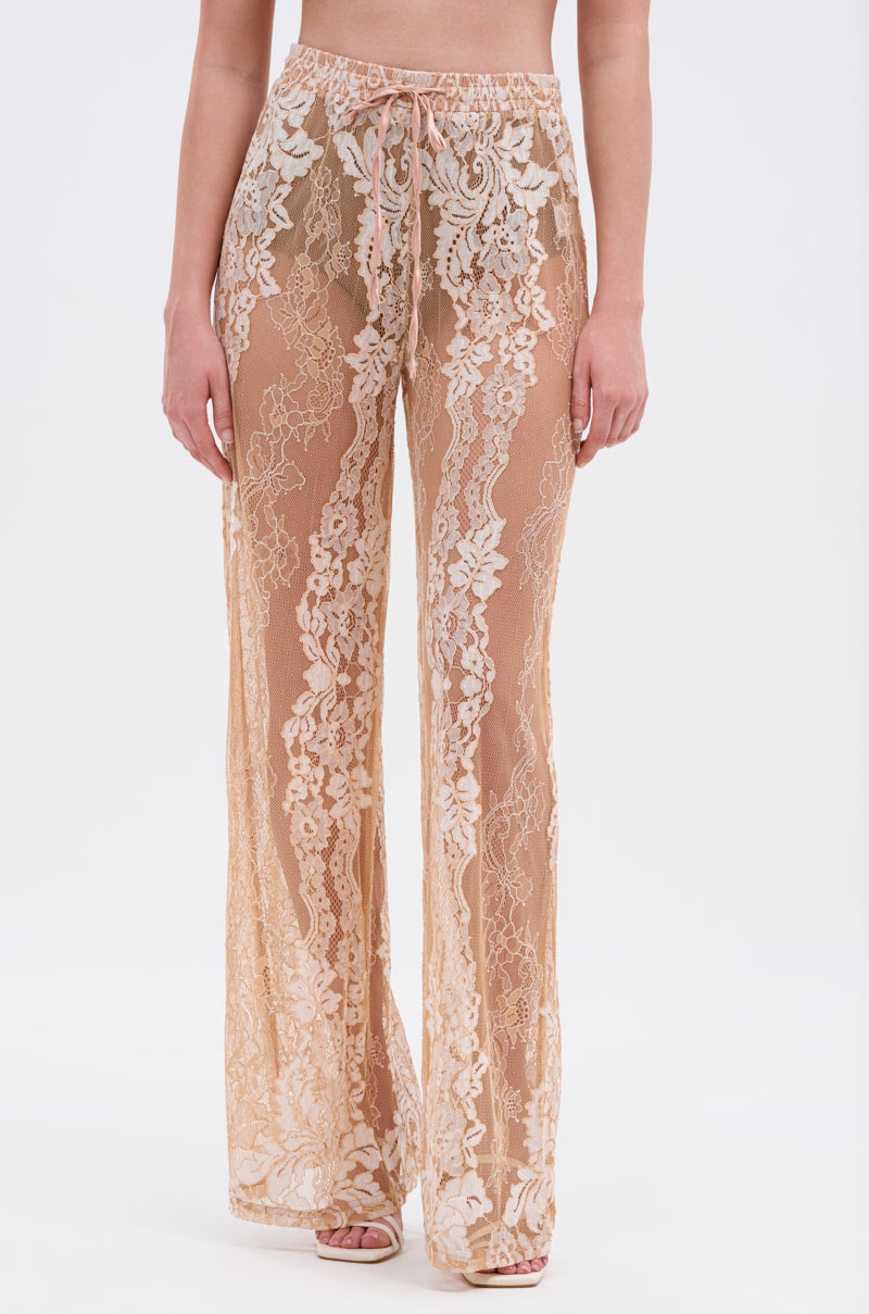 Wearing the RESORT VIBES WIDE LEG PALAZZO PANT—sheer, high-waisted floral lace with intricate patterns, wide legs, and an adjustable drawstring waist—someone stands against a plain white background. 1