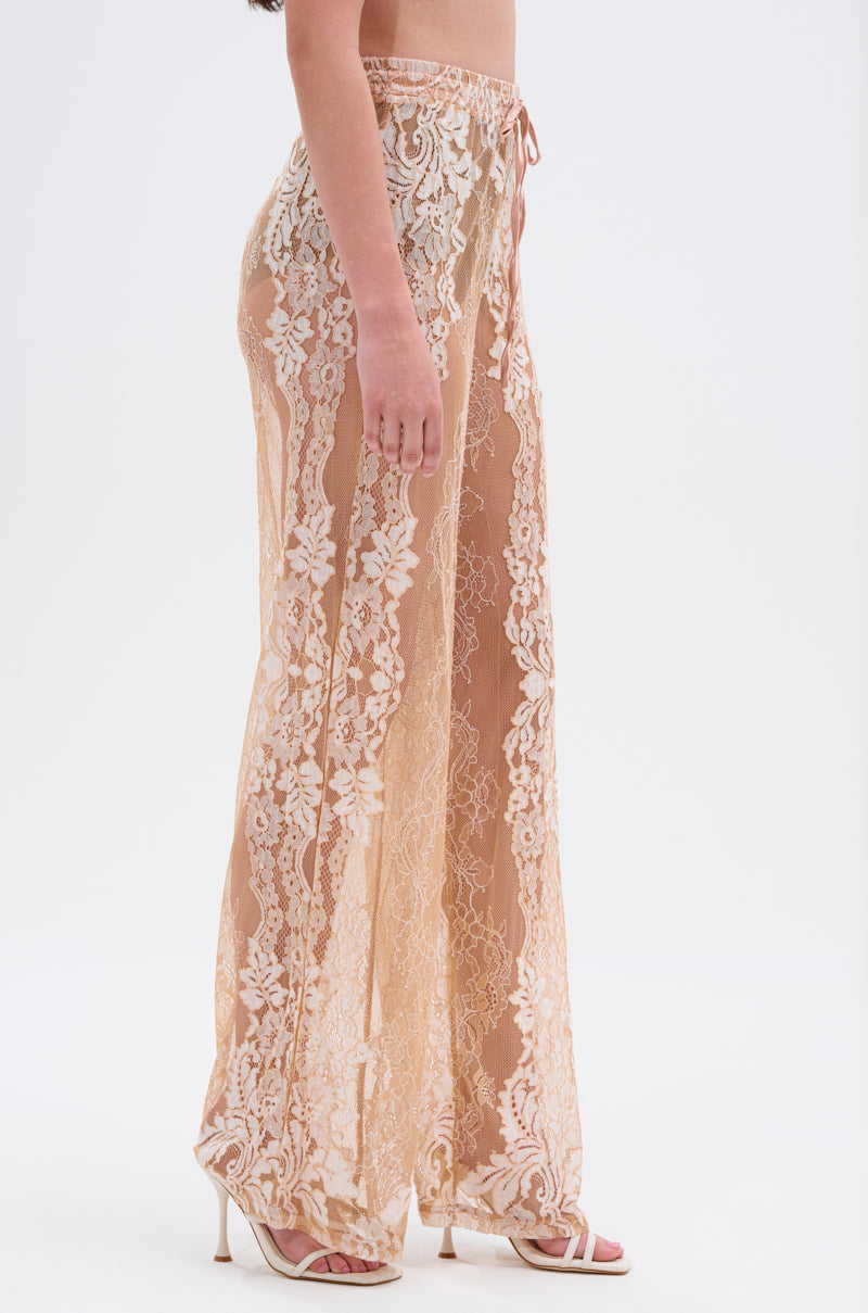 A woman models the RESORT VIBES WIDE LEG PALAZZO PANT in beige floral lace with white high-heeled sandals, set against a plain white background for a chic resort-inspired look. 2