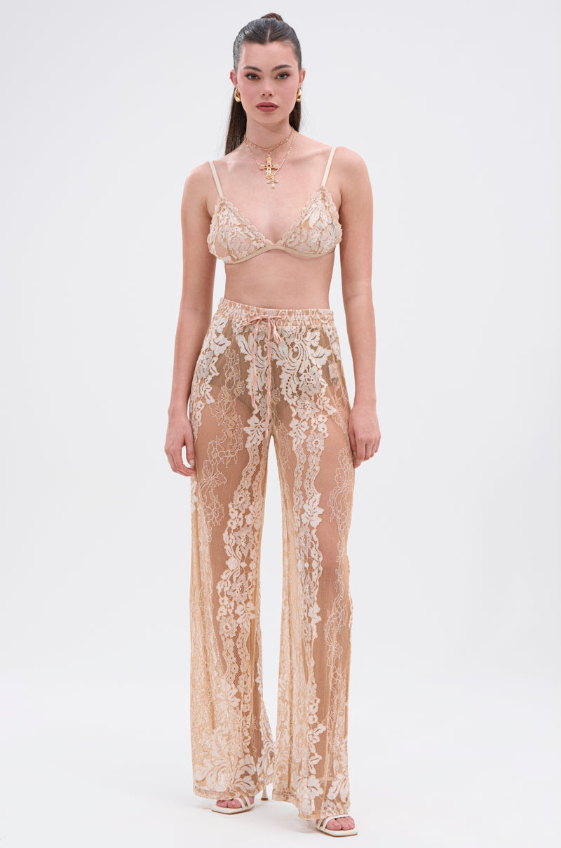 A woman faces forward in a sheer, floral lace bralette and the RESORT VIBES WIDE LEG PALAZZO PANT. Her long dark hair is styled back, accessorized with a necklace and earrings. The background is plain white. 4