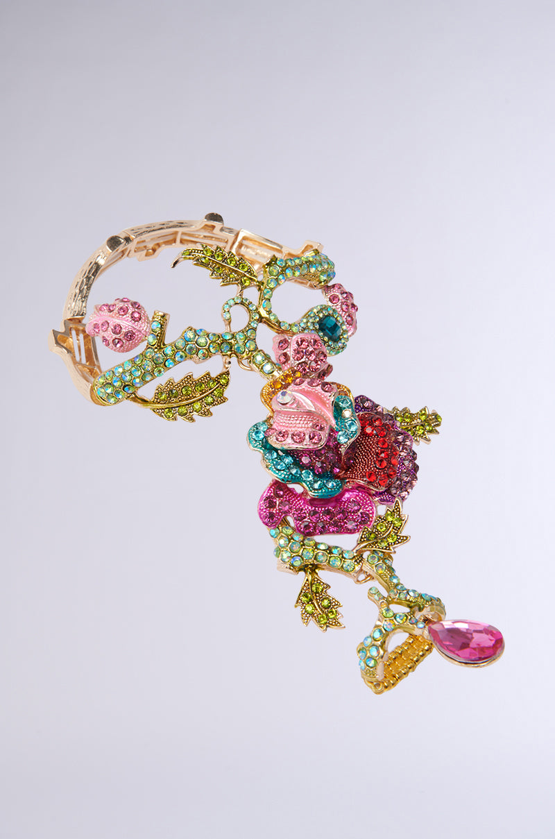 The MY SECRET GARDEN LUXE GEM BRACELET RING COMBO showcases intricate rhinestone-encrusted colorful gemstones and beads with pink, red, and turquoise stones, gold accents in floral designs of flowers and leaves, plus a teardrop-shaped pink gem.
