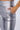 Close-up of a person wearing the ALWAYS WINNIN HIGH WAIST FAUX LEATHER PANT in metallic silver with their right hand in the pocket. The pants, crafted from stretchy metallic fabric, boast a shiny, sleek finish and a smooth skinny leg silhouette. The neutral background keeps the focus on these eye-catching faux leather leggings.