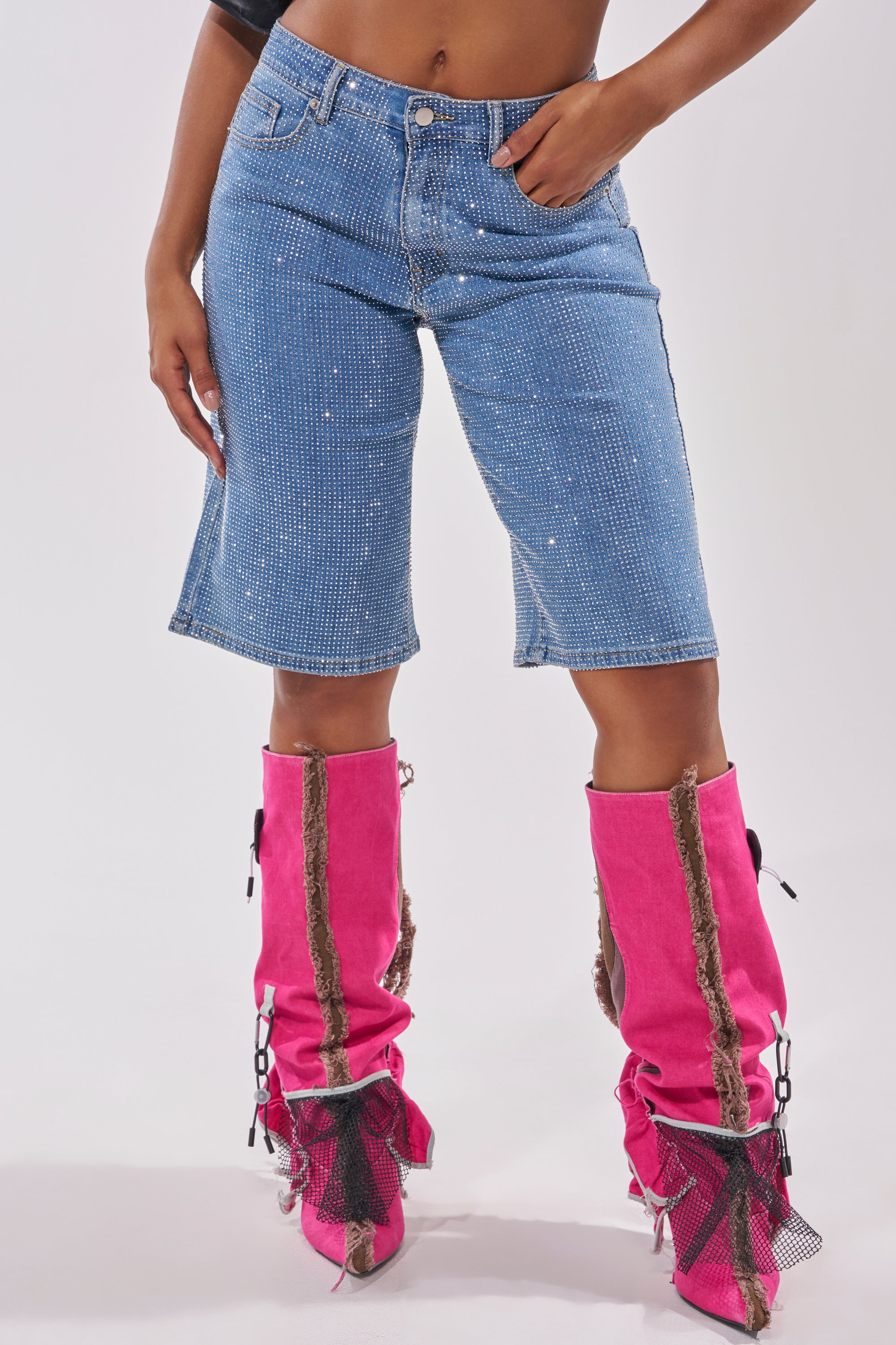 A person wearing BLING BLING RHINESTONE DARK BLUE DENIM BERMUDA SHORTS and bright pink knee-high boots with brown trim and black mesh accents, standing against a plain white background. 4