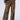 A person is wearing a black and white jacket paired with the MIMI CHEETAH PANT, featuring a brown cheetah print design with mid-rise waist, significant rips, and fraying on the front thighs. They are standing on a light background, which highlights their black platform shoes.