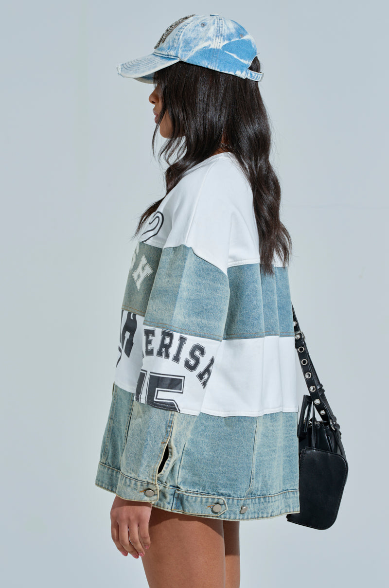 Wearing a blue and white color-block patchwork jacket, a denim cap, and the KEEP IT COOL DENIM MINI DRESS, a person with long dark hair carries a black bag with silver rivets against an academia-inspired light gray backdrop. 3
