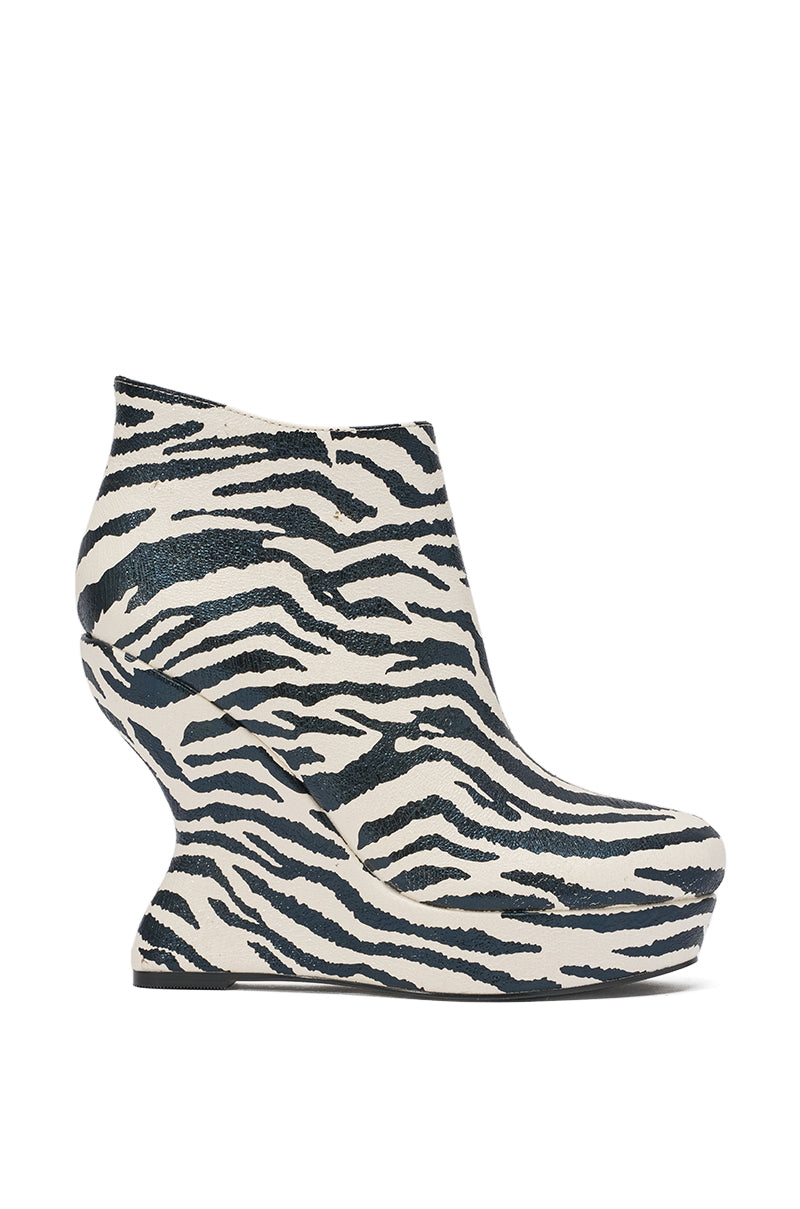 The AZALEA WANG ZEBRA PU PRINT WEDGE BOOTIE features a high heel, striking black-and-white zebra print, sculptural curved wedge sole, closed toe design, and luxe faux leather construction. 2