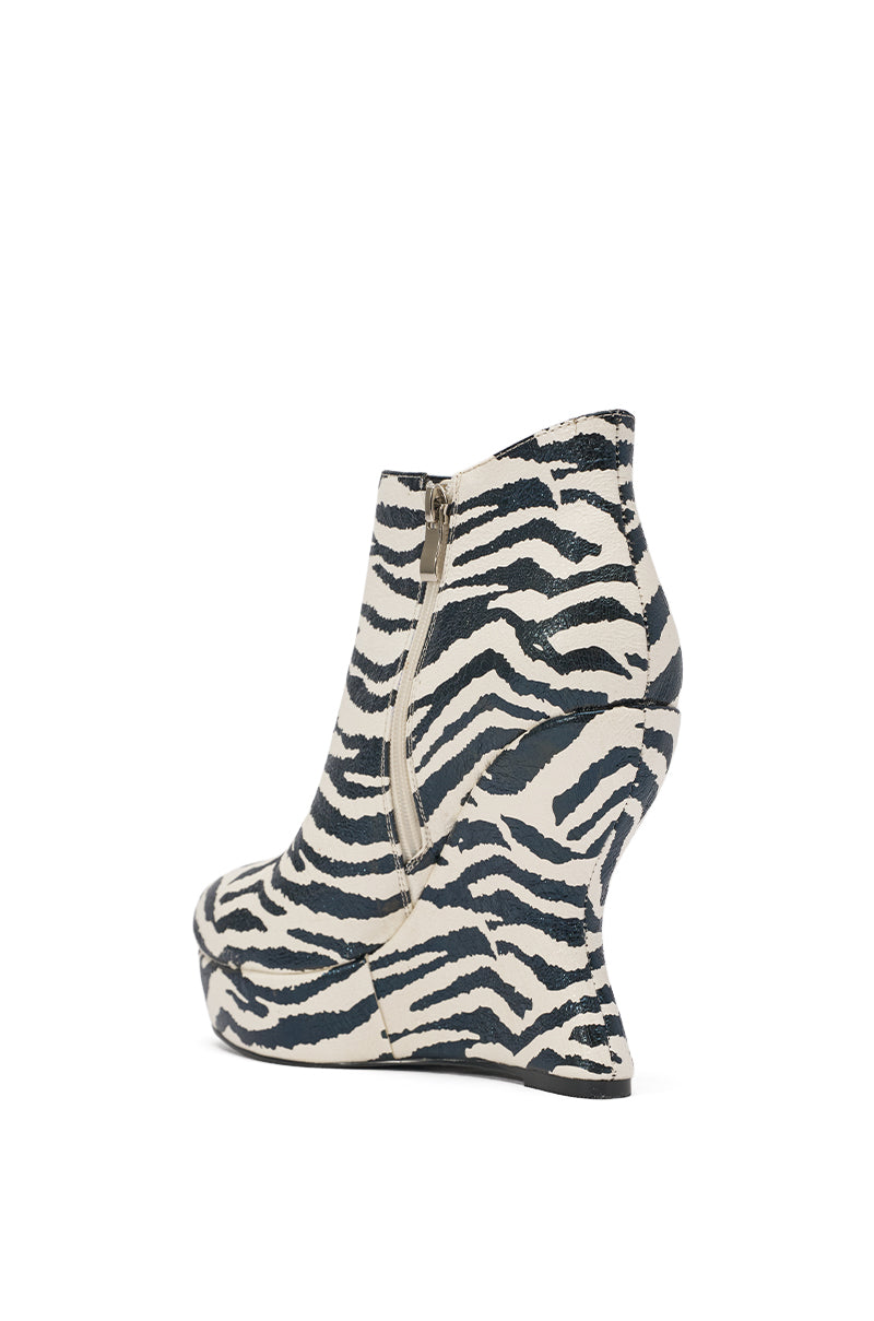 The AZALEA WANG ZEBRA PU PRINT WEDGE BOOTIE is a faux leather high-heeled bootie with a bold black and white zebra print, a sculptural curved wedge heel, and a side zipper. 4