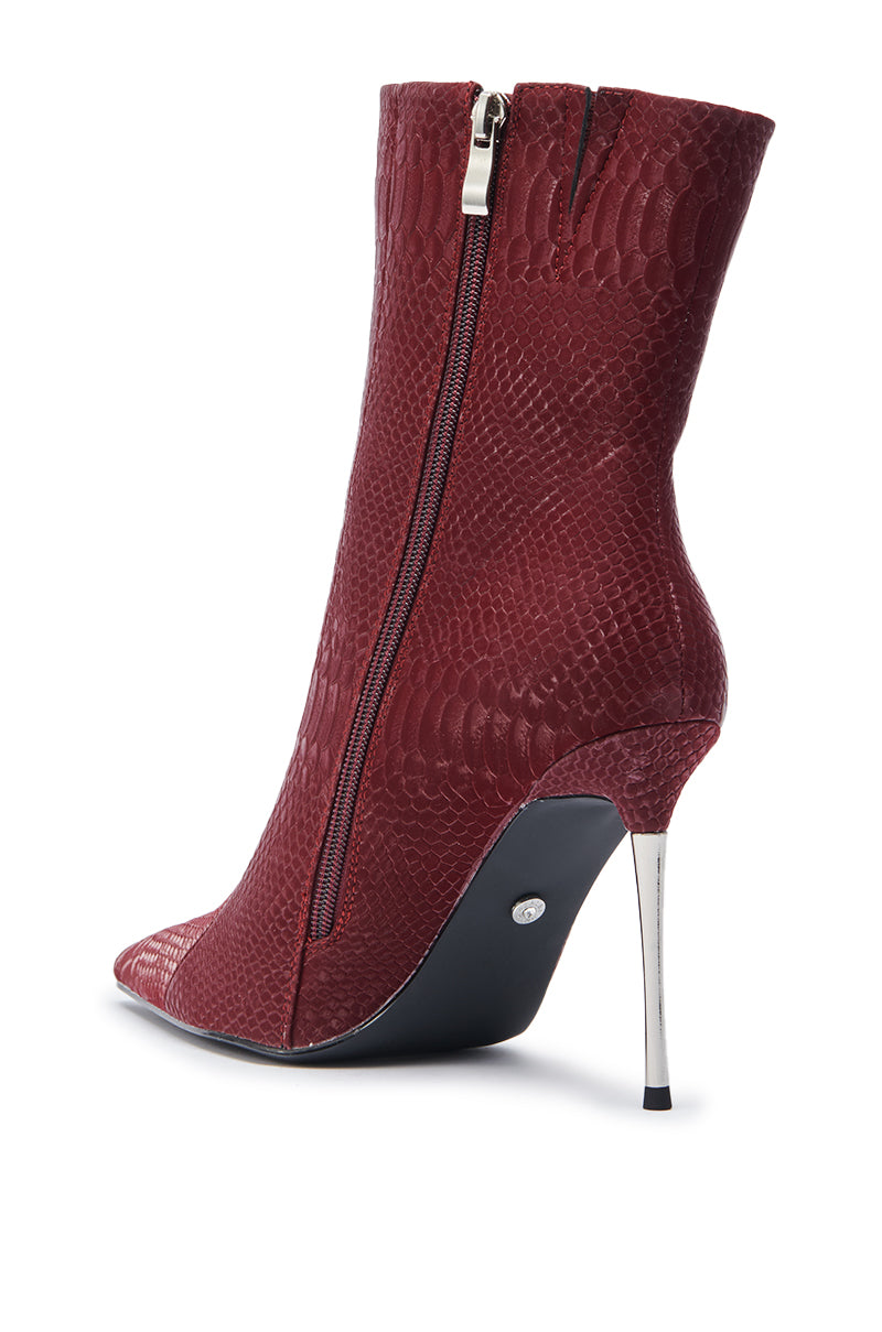 The AZALEA WANG CALEAN BURGUNDY BOOTIE features a red snakeskin pattern, pointed toe, slim silver stiletto heel, and side zipper. Shown from the side and slightly behind on a white background.