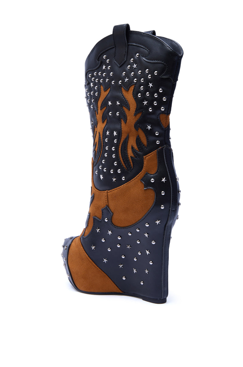 The AZALEA WANG CALLIA BLACK MULTI WESTERN WEDGE BOOTIE features black and brown faux leather, silver studs, flame patterns, a high wedge heel, and decorative stitching. This mid-calf bootie is photographed against a white background.