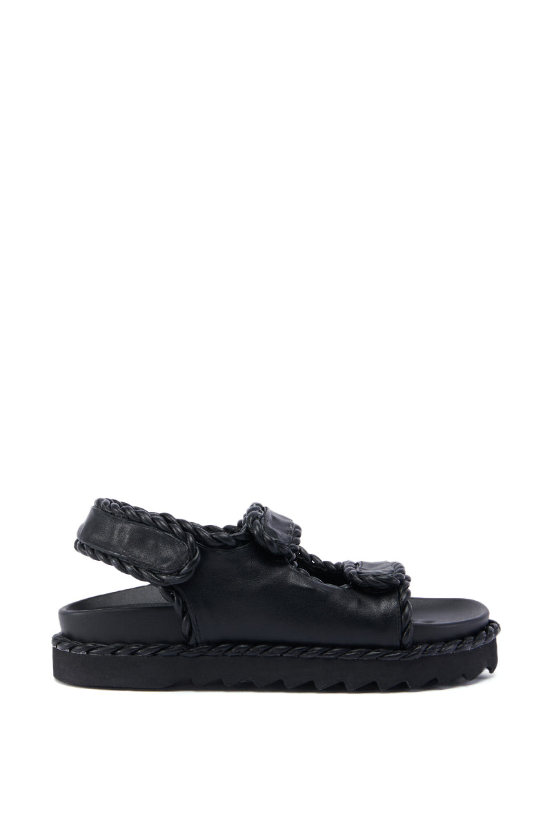The CAPE COD BLACK BRAIDED SANDAL is a casual and stylish summer shoe featuring a thick sole and braided straps across the top and back. The flat, slightly elevated platform has a textured bottom for grip, while the faux leather upper adds an extra touch of elegance.