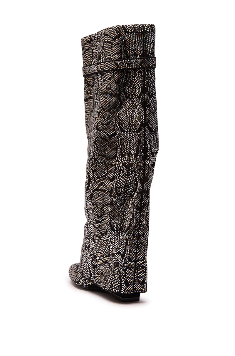 The AZALEA WANG CAPRICORN RHINESTONE SNAKE PATTERN WEDGE FOLD OVER BOOT features a high, slouched wedge design with a black and white snakeskin pattern, rounded toe, and flat sole, shown from the back on a white background.